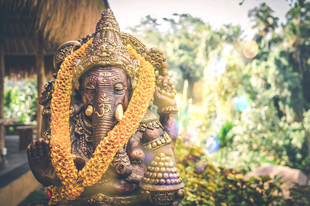 A buddhist elephant against a background of trees