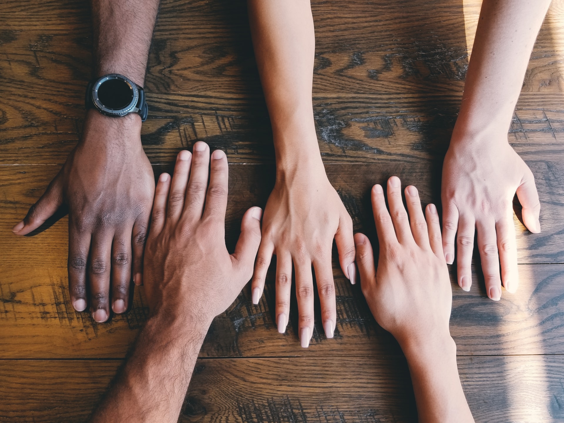 Hands of different ethnicities reaching out on table