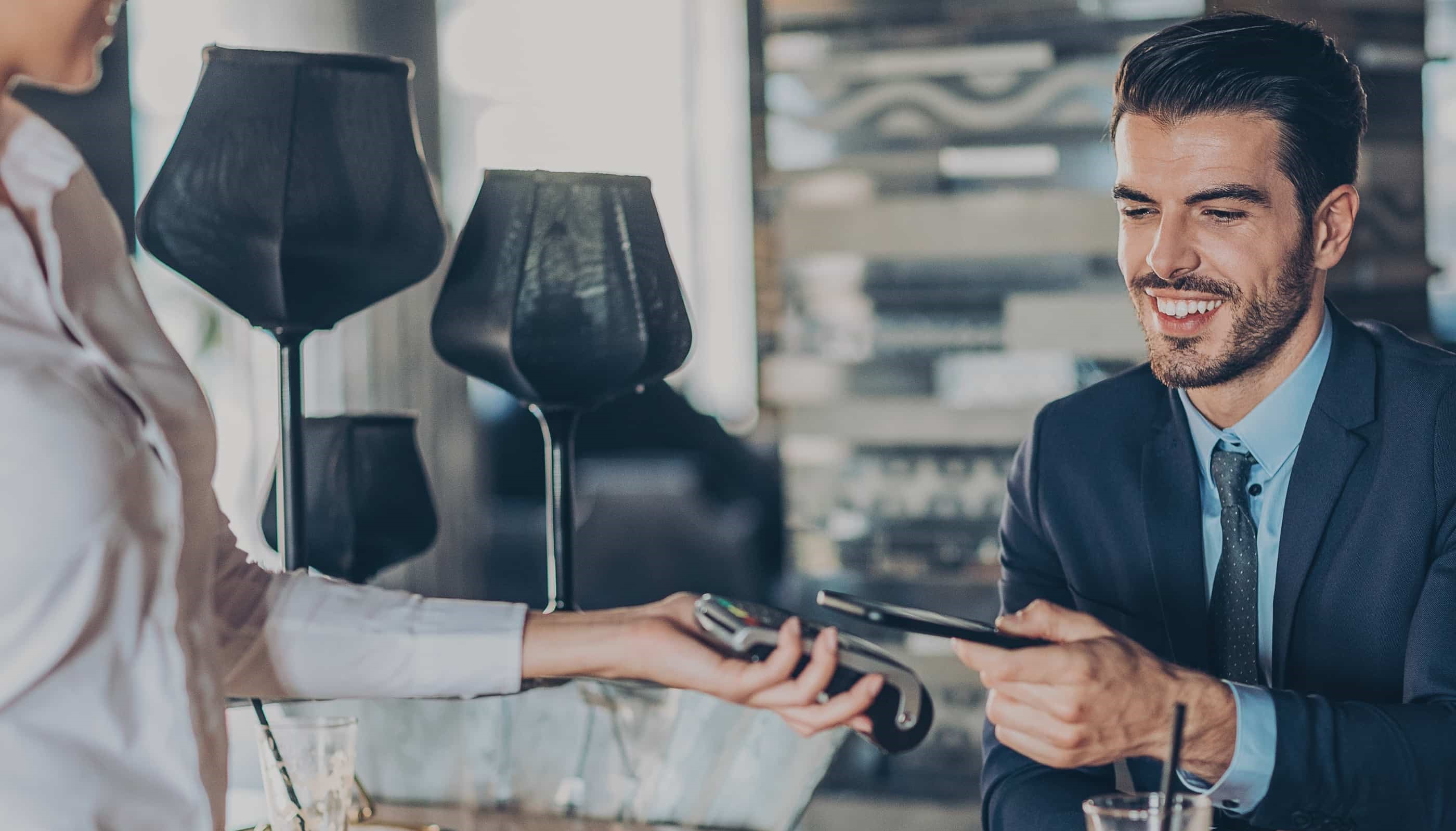 Man paying for drink with phone on a card machine