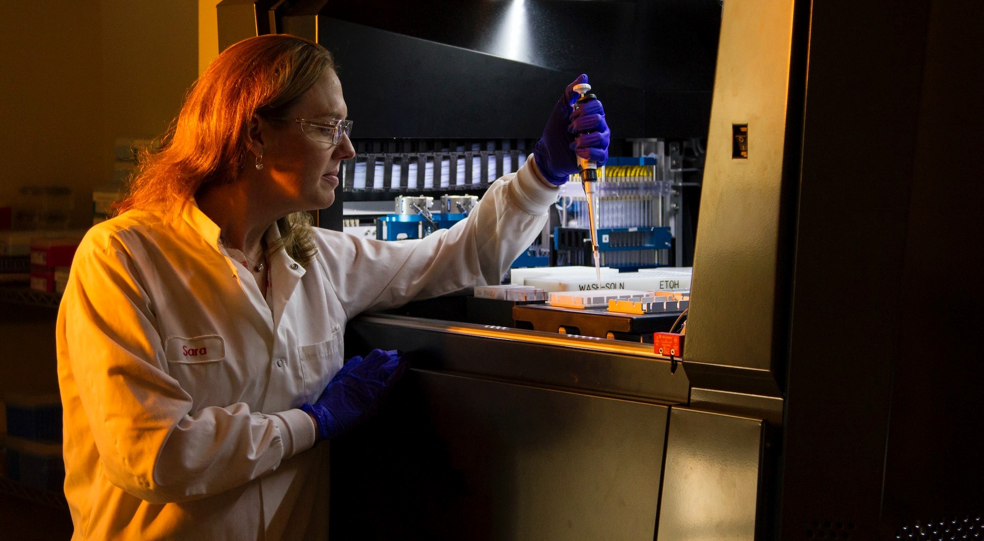 Scientist inserting samples into testing robot in laboratory